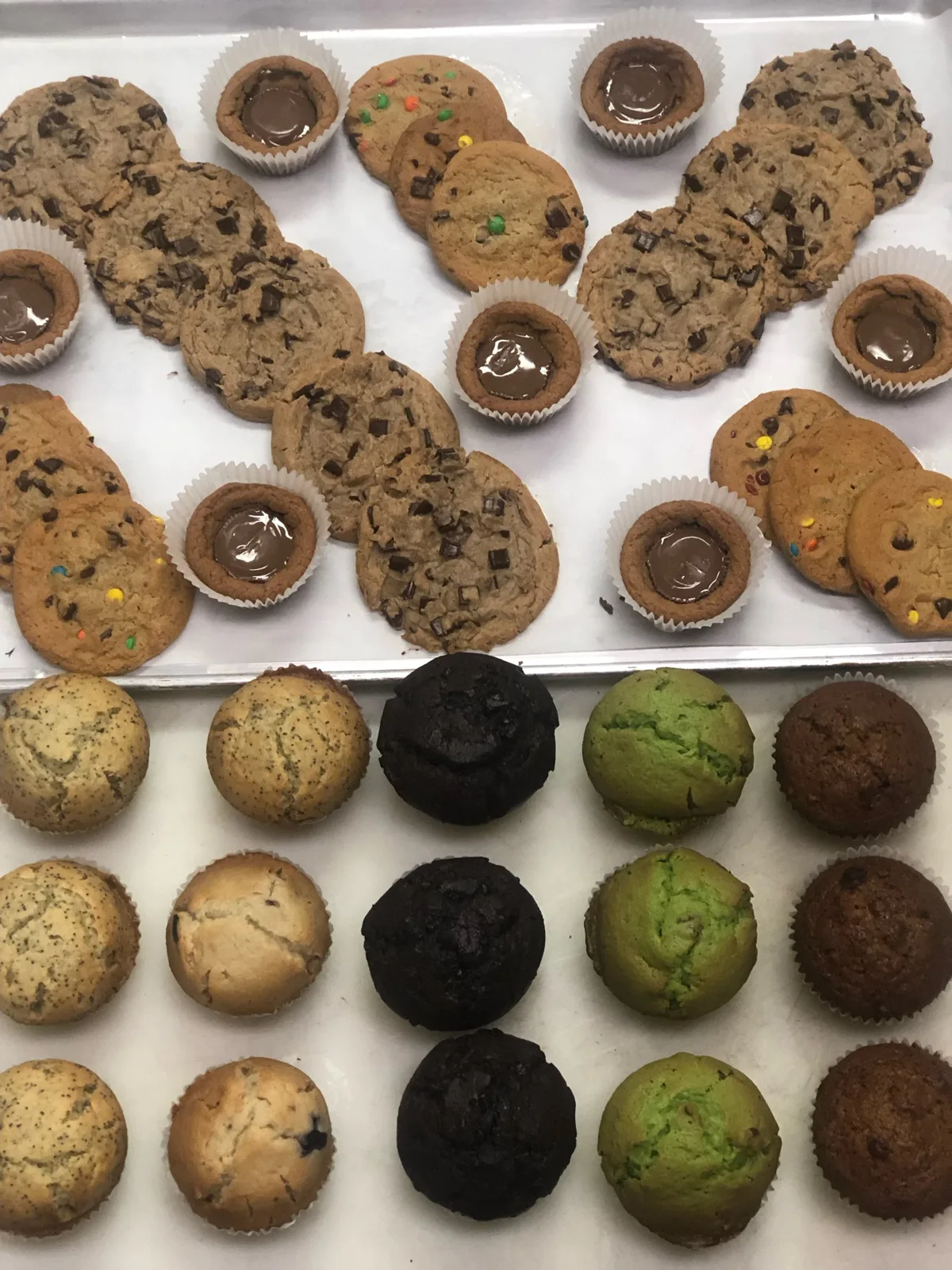 Fresh cookies and muffins on sheet pans